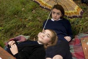 Best friends, Abby (Florence Pugh) and Lydia (Maisie Williams) lying on the grass in their school uniforms, drawing a tree.